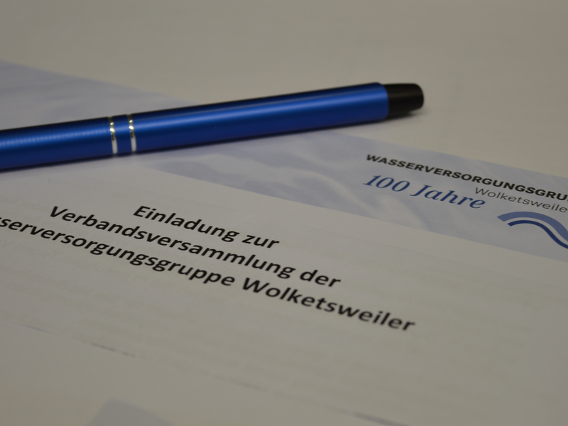 Ein Papier mit dem Briefkopf der Wasserversorgungsgruppe liegt auf einem weißen Tisch. Das Dokument trägt ide Überschrift "Einladung" auf dem Blatt Papier liegt ein blauer Kugelschreiber.