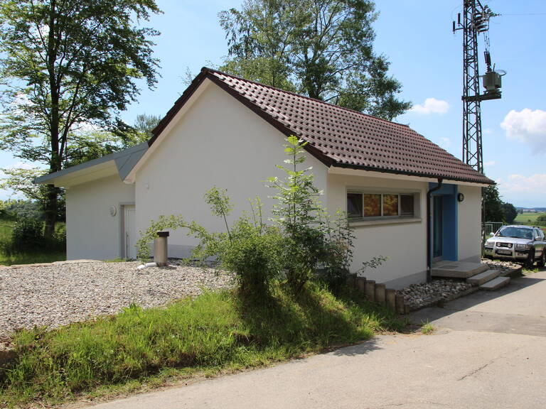 Ein Gebäude mit roten Ziegeln und weißer Fassade ist am Straßenrand zu sehen, der Hochbehälter Rolgenmoos